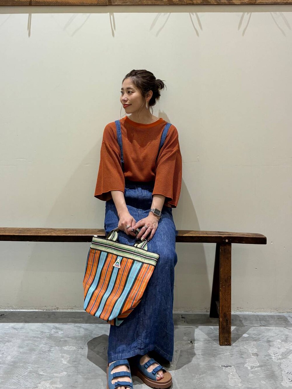 ブルー系のスカート、ブルー系のサンダル、オレンジ系のトートバッグを着用したレディースの春コーディネートの5枚目の写真