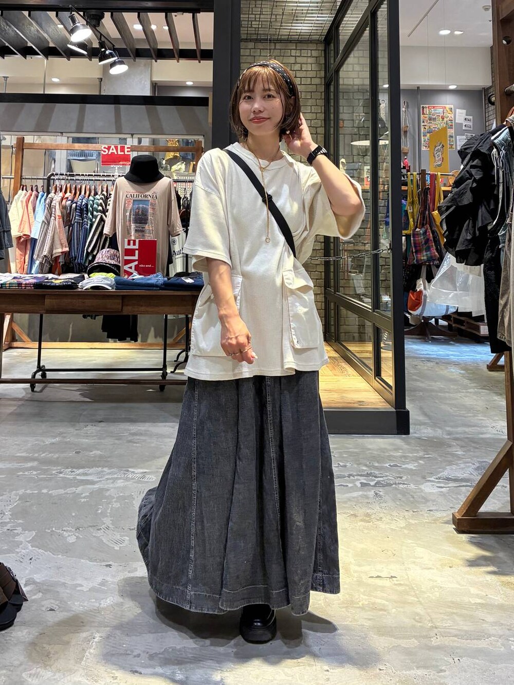 グレー系のスカート、ベージュ系のTシャツ/カットソー、ブラック系のショルダーバッグを着用したレディースの夏コーディネートの3枚目の写真