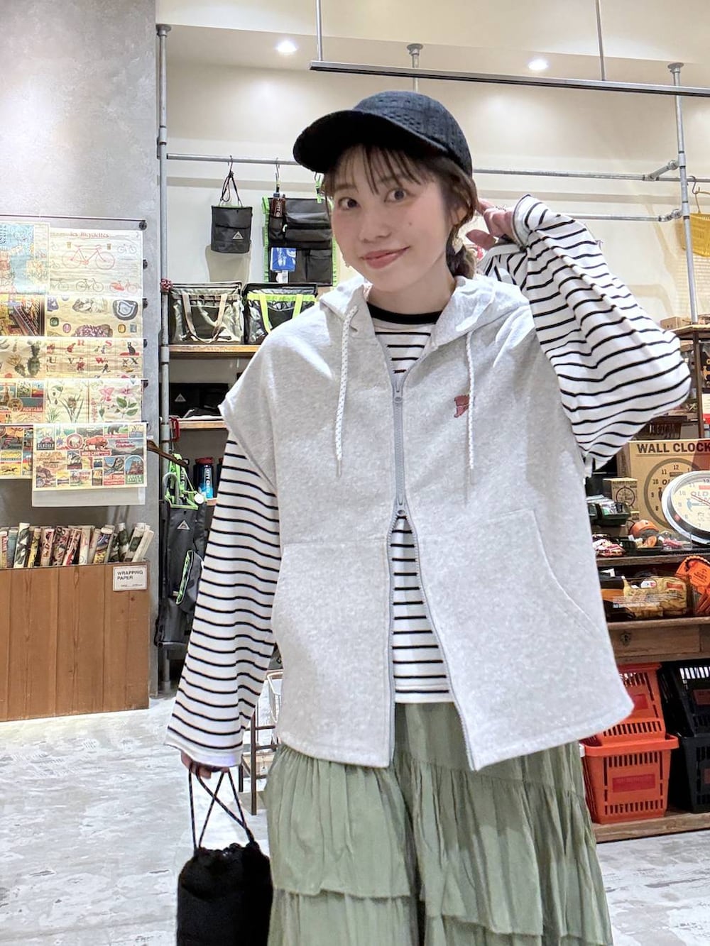 ブラック系のショルダーバッグ、ホワイト系のTシャツ/カットソー、グレー系のベストを着用したレディースの春コーディネートの6枚目の写真