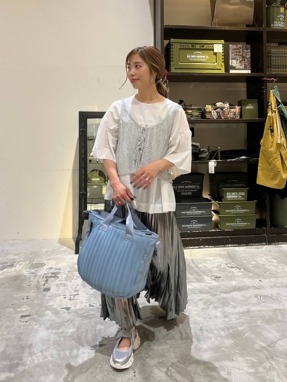 グレー系のスカート、ブルー系のトートバッグ、シルバー系のスニーカーを着用したレディースの夏コーディネートの2枚目の写真