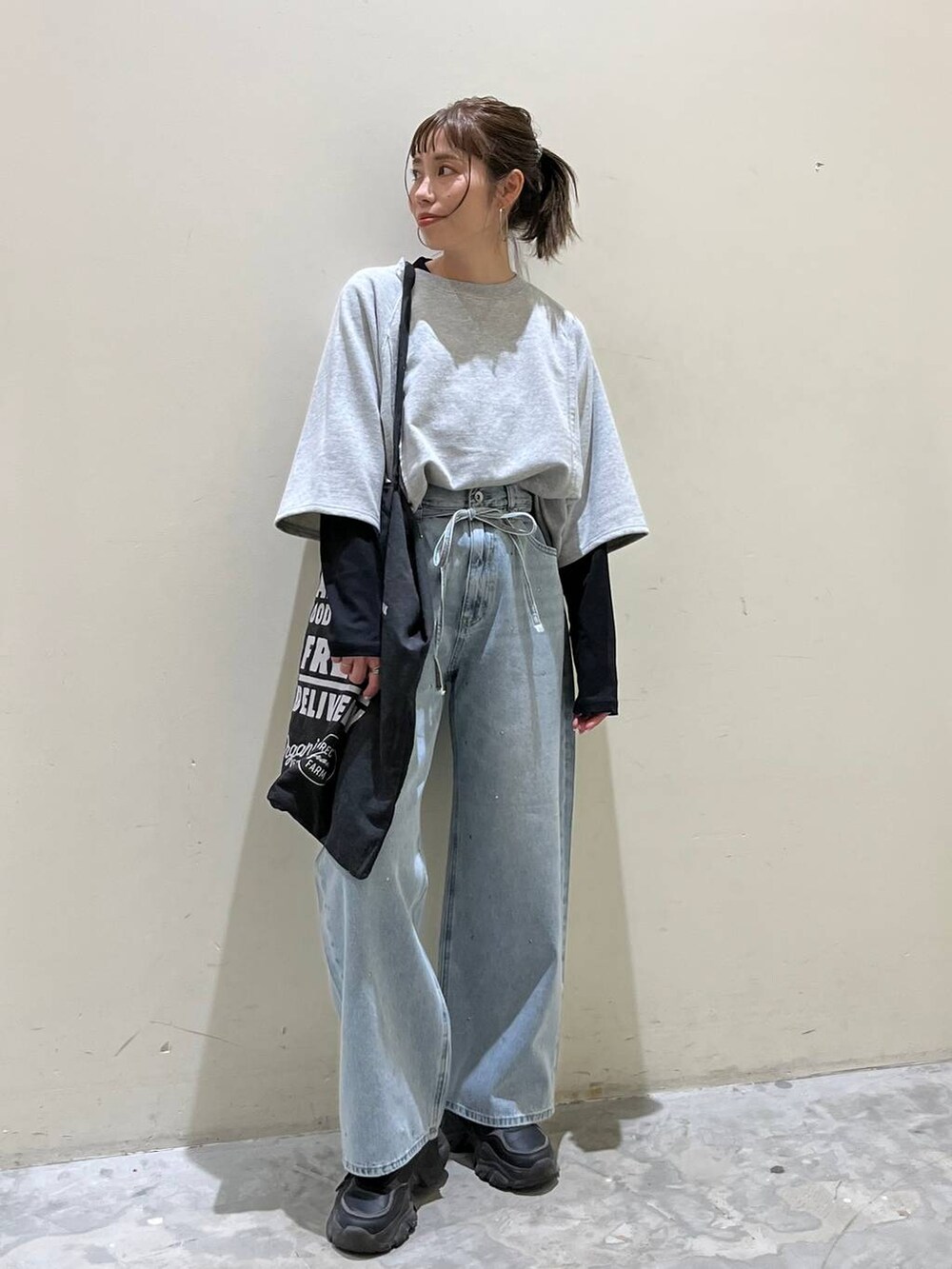 グレー系のトートバッグ、グレー系のTシャツ/カットソー、ブルー系のデニムパンツを着用したレディースの春コーディネートの3枚目の写真