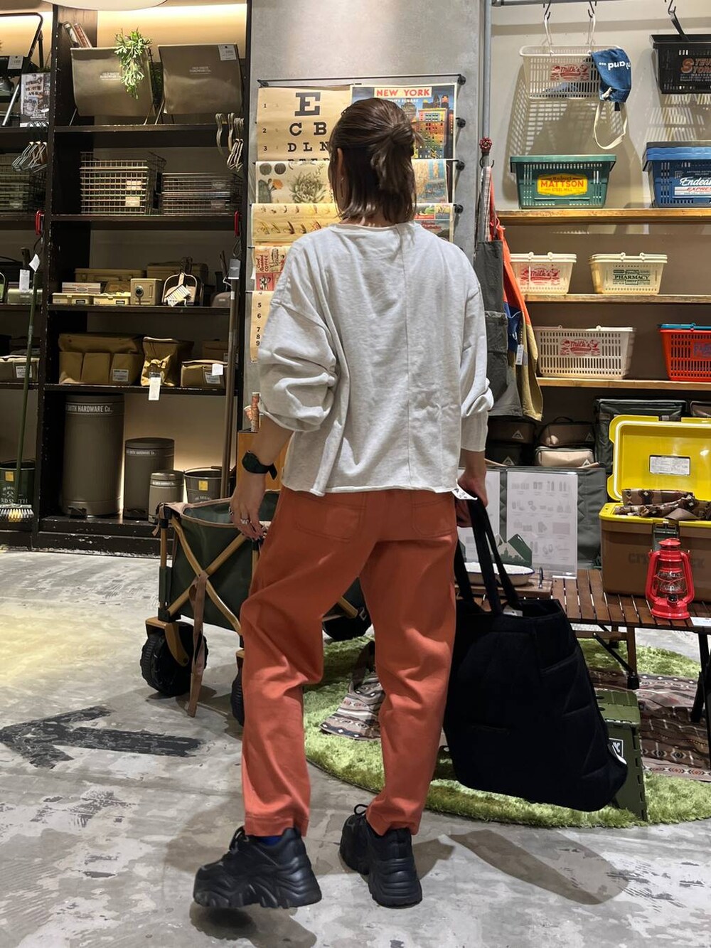 ブラック系のトートバッグ、オレンジ系のその他パンツ、ホワイト系のTシャツ/カットソーを着用したレディースの秋コーディネートの5枚目の写真