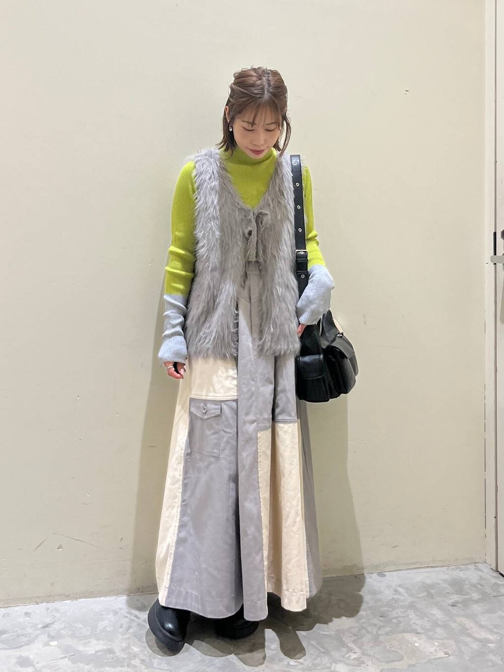 グリーン系のニット/セーター、ブラック系のブーツ、ブラック系のショルダーバッグを着用したレディースの冬コーディネートの6枚目の写真