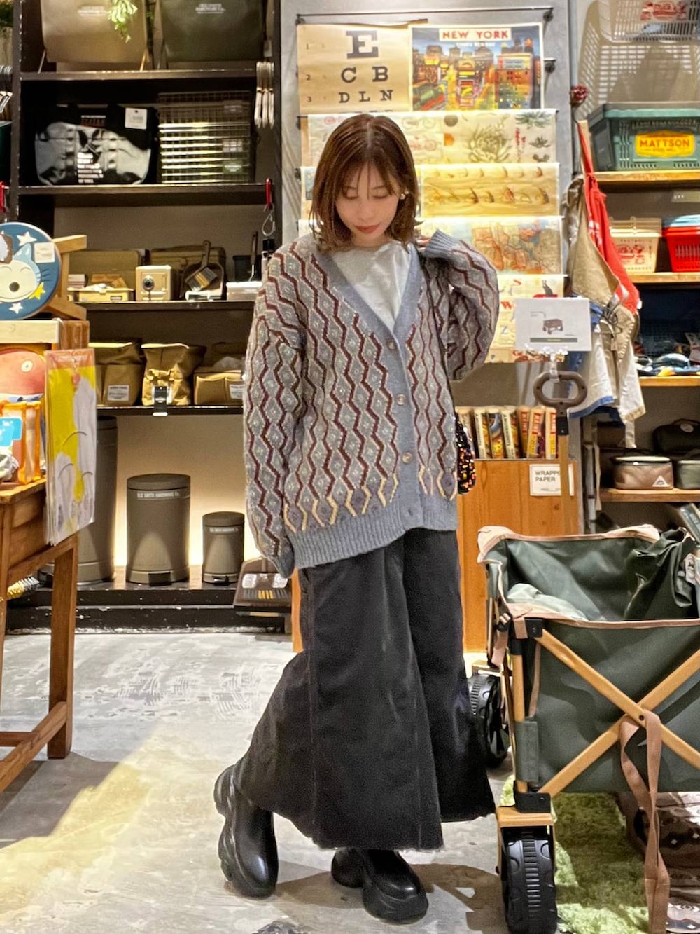 グレー系のスカート、ブルー系のカーディガン/ボレロ、ブラック系のブーツを着用したレディースの秋コーディネートの3枚目の写真