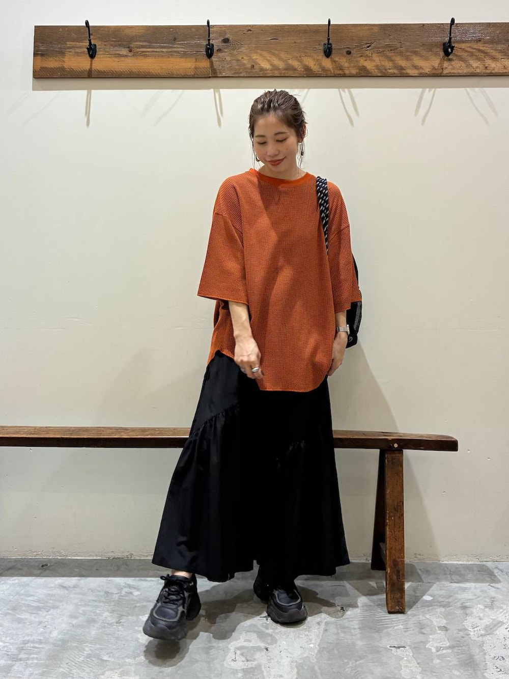 ブラック系のスカート、オレンジ系のTシャツ/カットソー、ブラック系のバックパック/リュックを着用したレディースの夏コーディネートの8枚目の写真