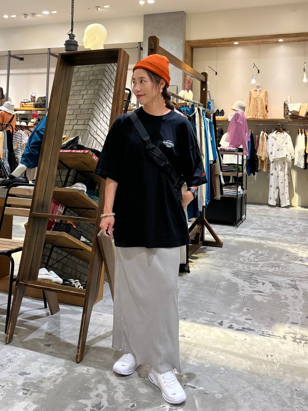 ブラック系のショルダーバッグ、グレー系のスカート、ブラック系のTシャツ/カットソーを着用したレディースの夏コーディネートの2枚目の写真