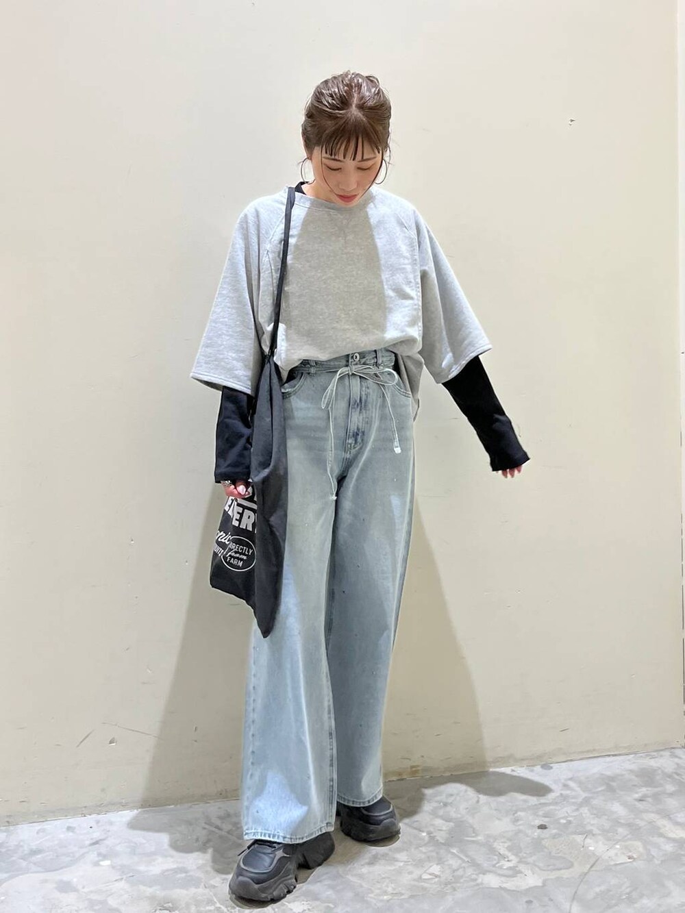 グレー系のトートバッグ、グレー系のTシャツ/カットソー、ブルー系のデニムパンツを着用したレディースの春コーディネートの7枚目の写真