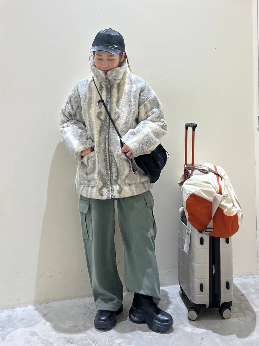 グレー系のブルゾン、ブラック系のショルダーバッグ、ブラック系のブーツを着用したレディースの冬コーディネートの3枚目の写真