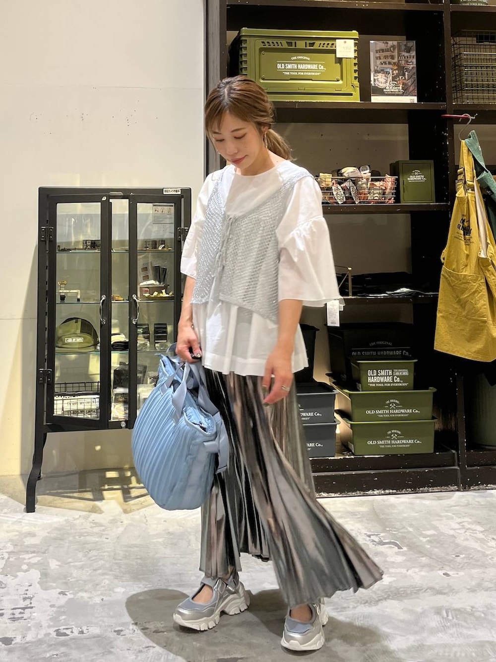 グレー系のスカート、ブルー系のトートバッグ、シルバー系のスニーカーを着用したレディースの夏コーディネートの7枚目の写真