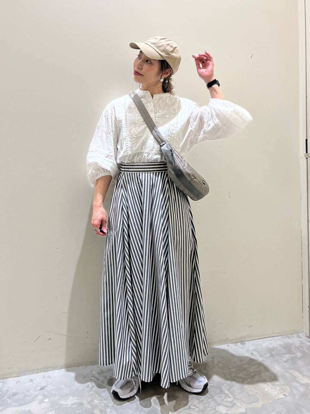 グレー系のショルダーバッグ、グレー系のスニーカー、ブルー系のスカートを着用したレディースの春コーディネートの4枚目の写真