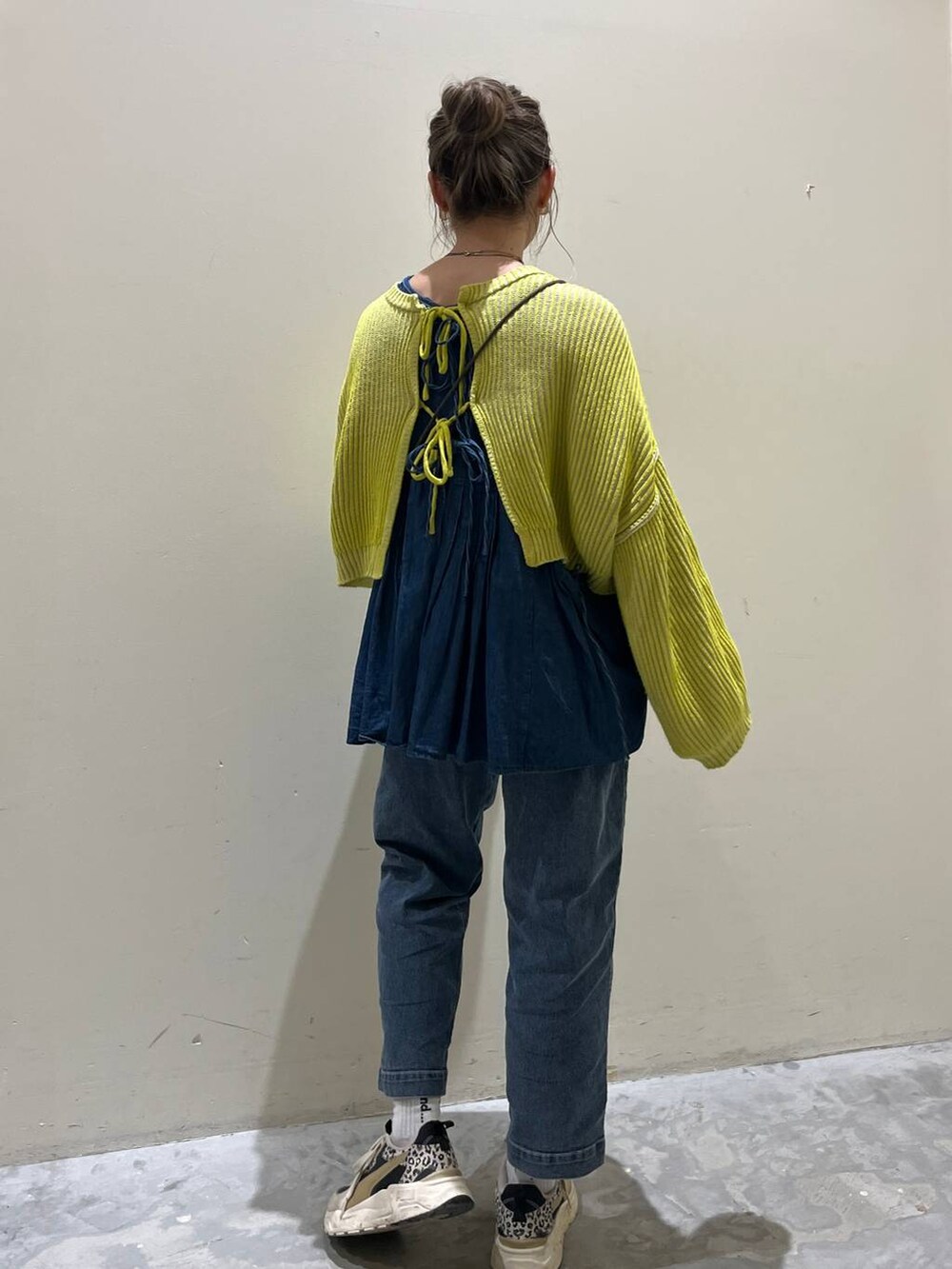 イエロー系のニット/セーター、ブルー系のその他パンツ、ホワイト系のショルダーバッグを着用したレディースの春コーディネートの4枚目の写真