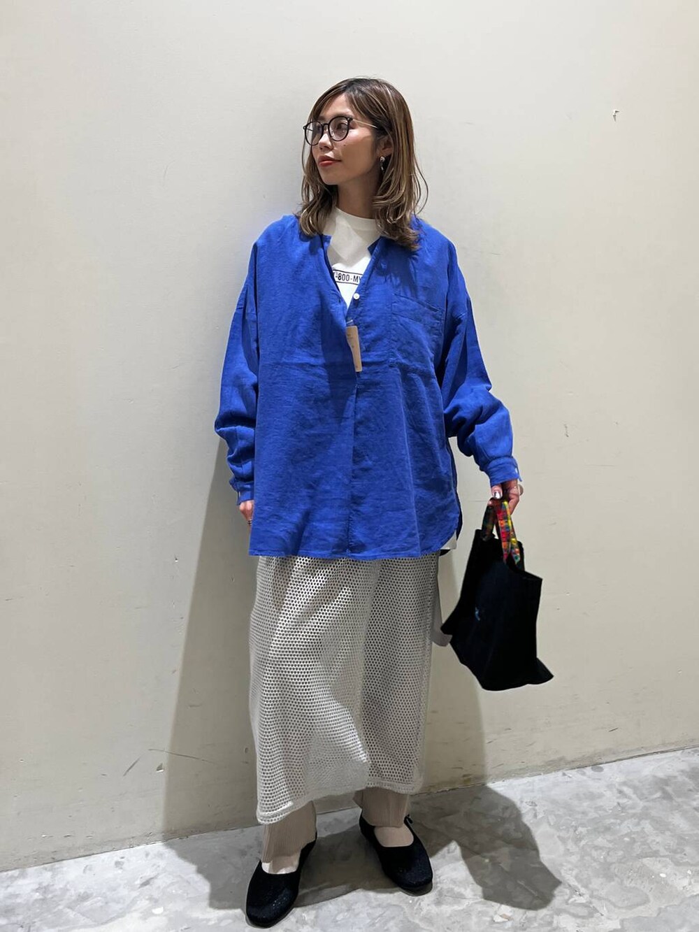 グレー系のスカート、ブラック系のその他シューズ、ブラック系のトートバッグを着用したレディースの春コーディネートの2枚目の写真