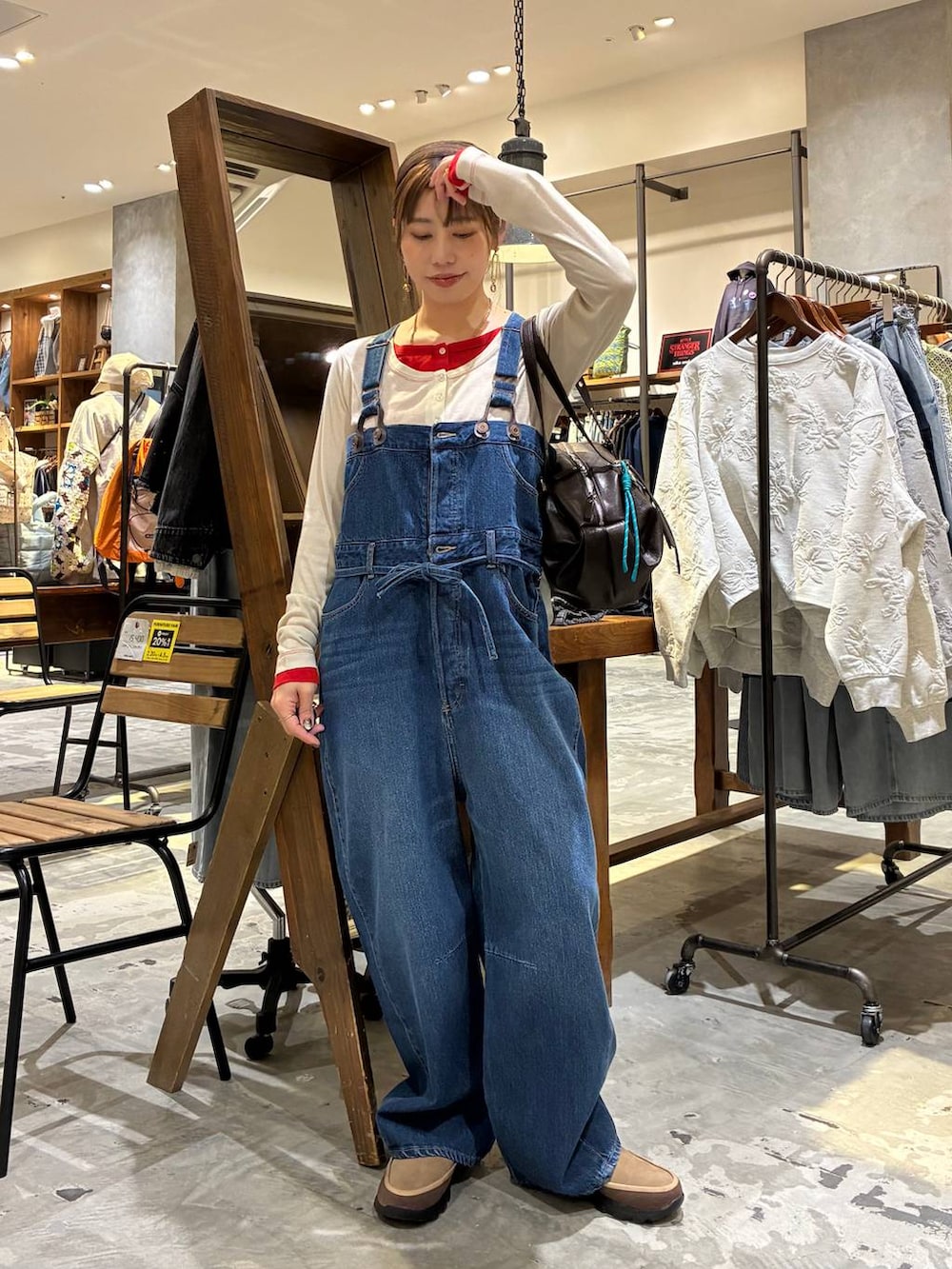 ブラウン系のボストンバッグ、ベージュ系のTシャツ/カットソー、ブルー系のサロペット/オーバーオールを着用したレディースの冬コーディネートの6枚目の写真