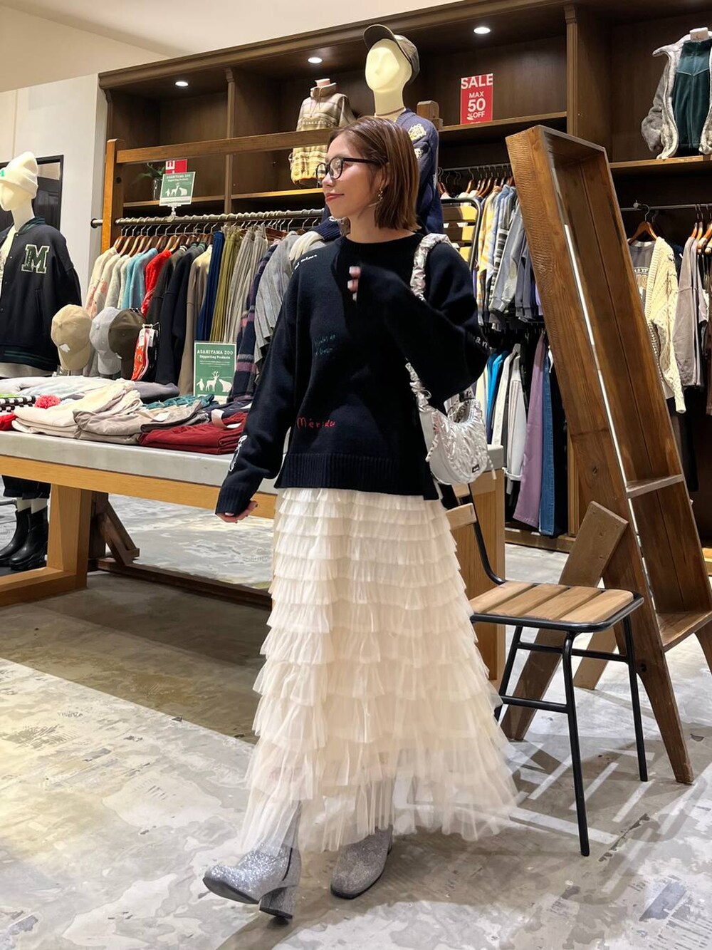 グレー系のブーツ、ホワイト系のスカート、シルバー系のショルダーバッグを着用したレディースの冬コーディネートの2枚目の写真