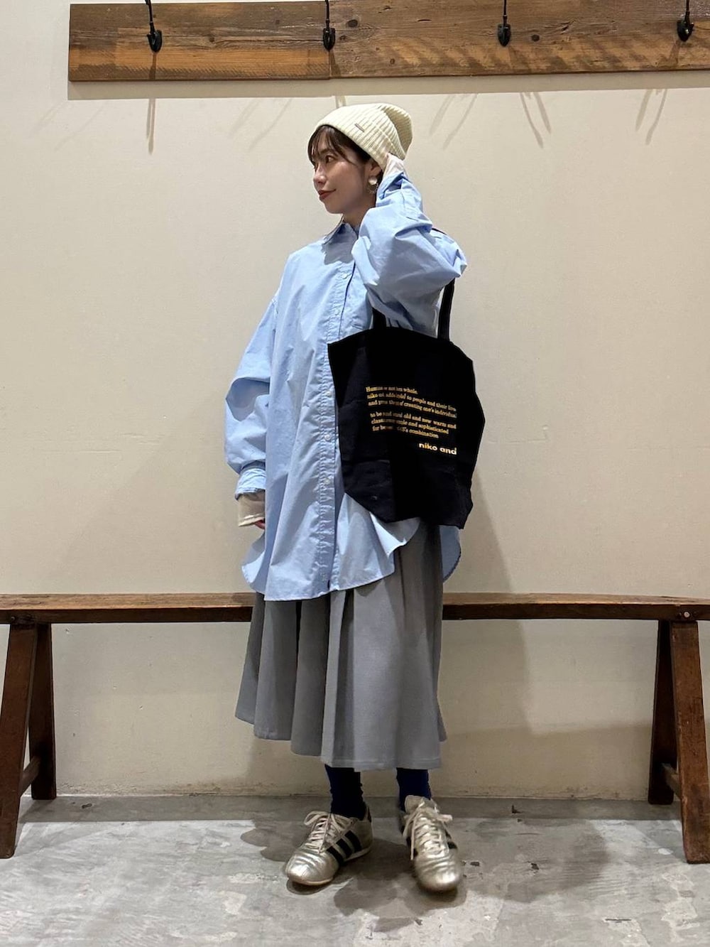 ブルー系のトートバッグ、ゴールド系のスニーカー、ベージュ系のTシャツ/カットソーを着用したレディースの冬コーディネートの6枚目の写真