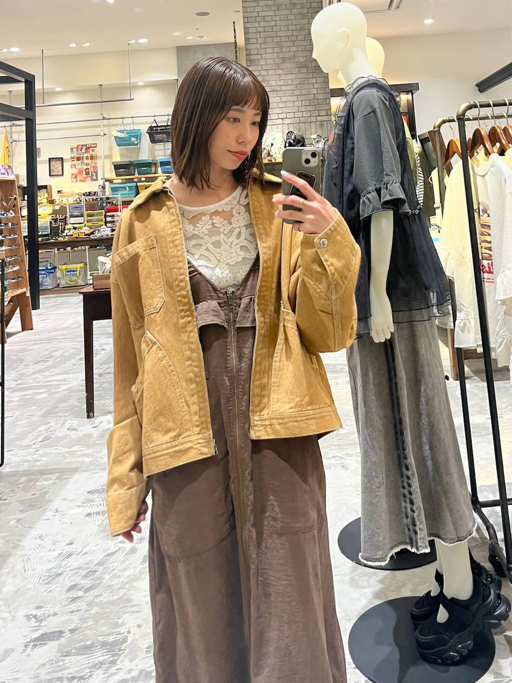 ブラウン系のジャンパースカート、ホワイト系のトートバッグ、ブラウン系のデニムジャケットを着用したレディースの春コーディネートの3枚目の写真