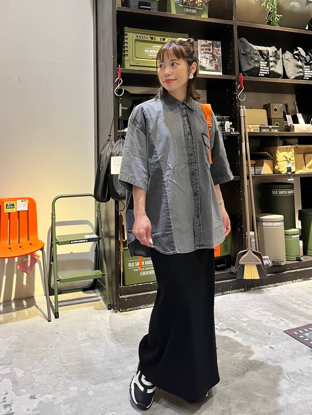 ブラック系のスカート、ブラック系のスニーカー、オレンジ系のバックパック/リュックを着用したレディースの春コーディネートの2枚目の写真