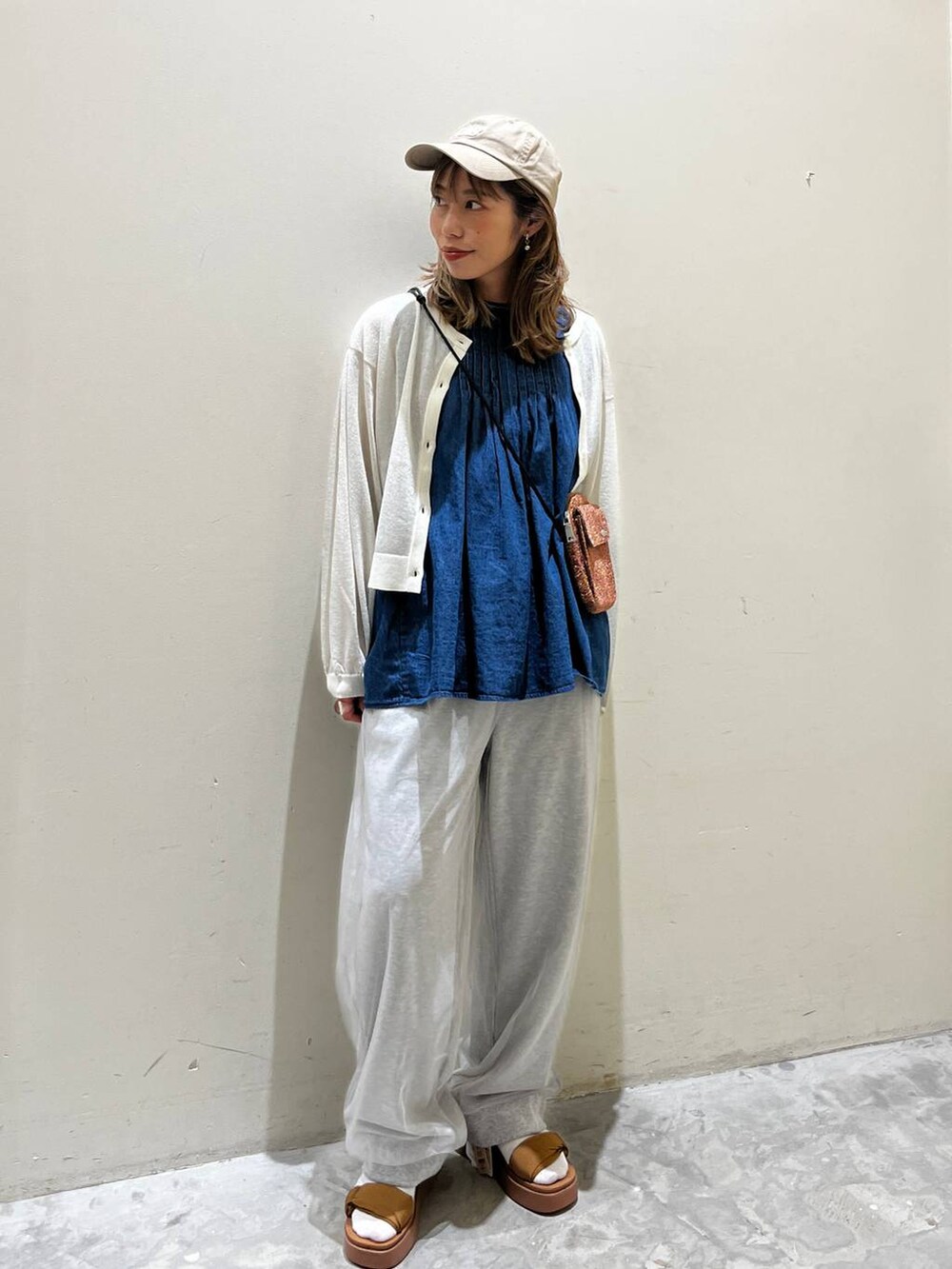 イエロー系のサンダル、ブルー系のベスト、オレンジ系のショルダーバッグを着用したレディースの春コーディネートの6枚目の写真