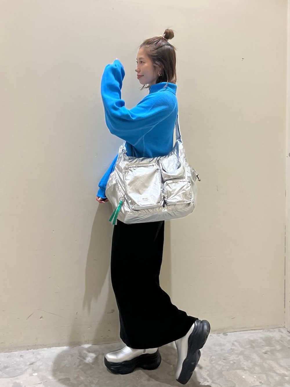 シルバー系のショルダーバッグ、グレー系のブーツ、ブラック系のスカートを着用したレディースの冬コーディネートの4枚目の写真