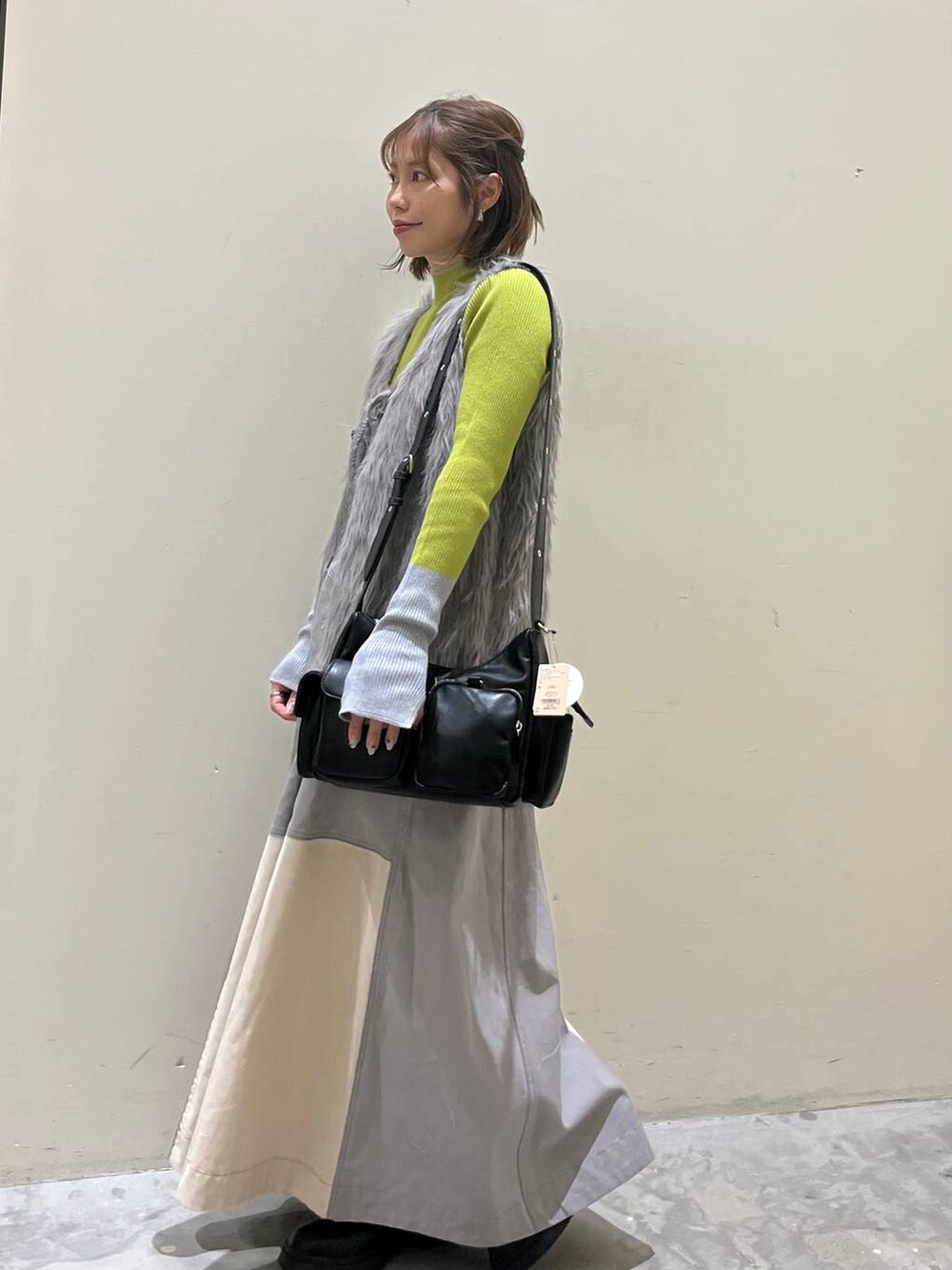 グリーン系のニット/セーター、ブラック系のブーツ、ブラック系のショルダーバッグを着用したレディースの冬コーディネートの5枚目の写真