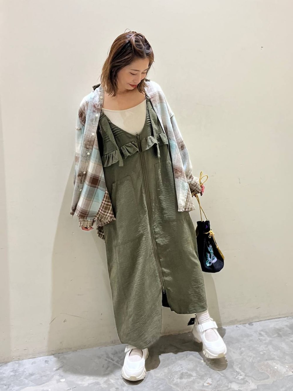 グリーン系のシャツ/ブラウス、グリーン系のジャンパースカート、ベージュ系のスニーカーを着用したレディースの秋コーディネートの2枚目の写真