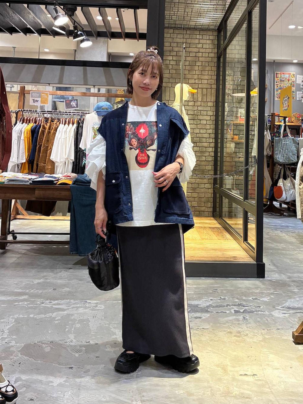 ホワイト系のスカート、ブラック系のスニーカー、ホワイト系のTシャツ/カットソーを着用したレディースの夏コーディネートの3枚目の写真