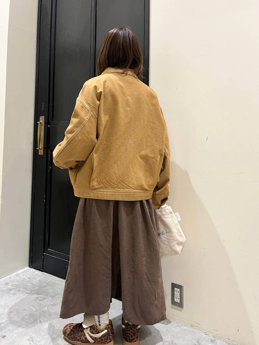 ブラウン系のジャンパースカート、ホワイト系のトートバッグ、ブラウン系のデニムジャケットを着用したレディースの春コーディネートの6枚目の写真