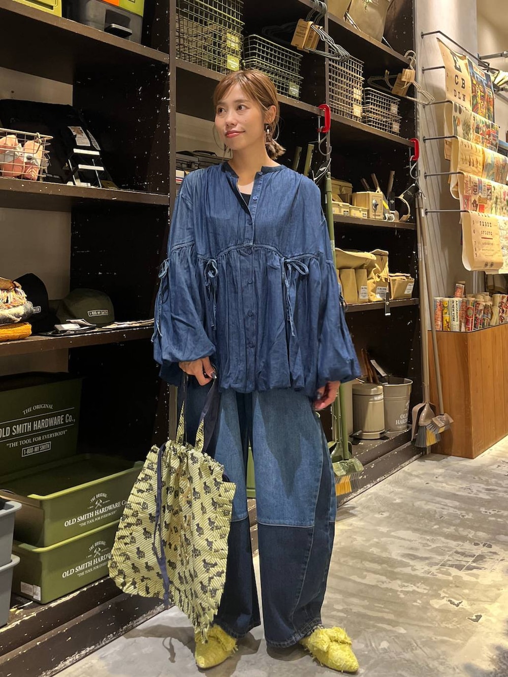 ベージュ系のトートバッグ、ブルー系のデニムパンツ、イエロー系のバレエシューズを着用したレディースの秋コーディネートの4枚目の写真