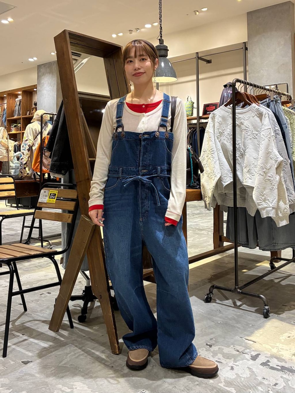 ブラウン系のボストンバッグ、ベージュ系のTシャツ/カットソー、ブルー系のサロペット/オーバーオールを着用したレディースの冬コーディネートの3枚目の写真