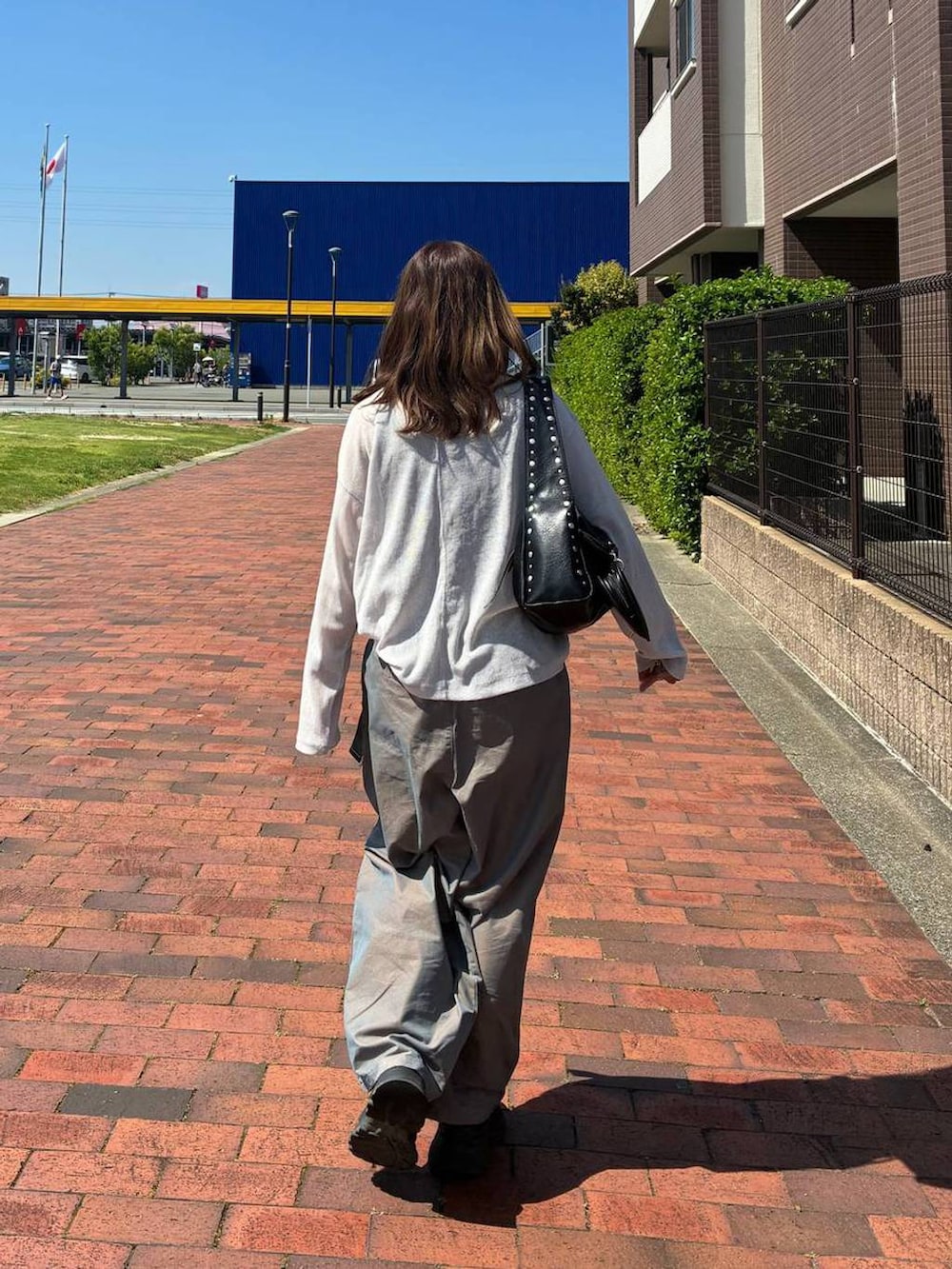 ブラック系のハンドバッグ、グレー系のTシャツ/カットソー、グリーン系のチノパンツを着用したレディースの夏コーディネートの3枚目の写真