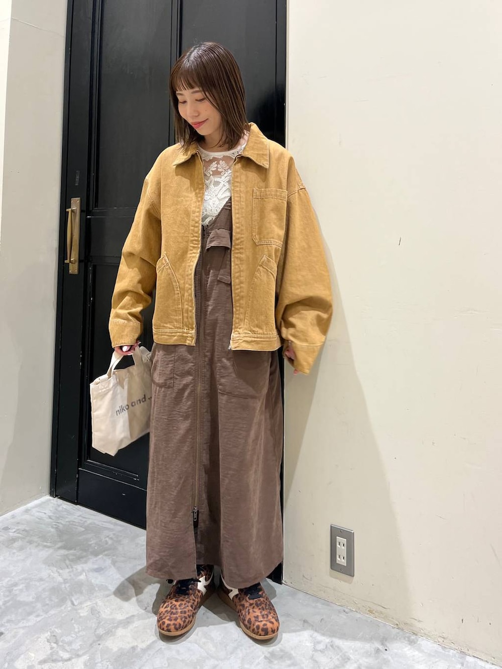 ブラウン系のジャンパースカート、ホワイト系のトートバッグ、ブラウン系のデニムジャケットを着用したレディースの春コーディネートの4枚目の写真