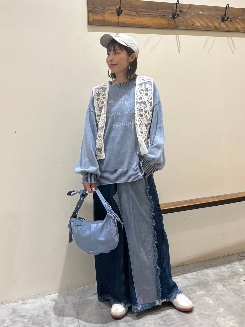 ベージュ系のスニーカー、ブルー系のデニムスカート、ブルー系のショルダーバッグを着用したレディースの冬コーディネートの6枚目の写真