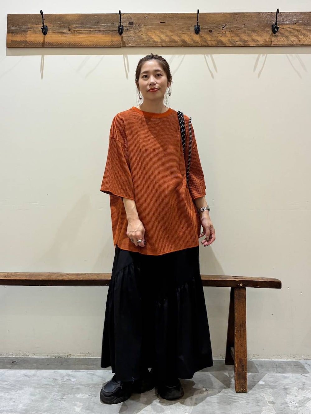ブラック系のスカート、オレンジ系のTシャツ/カットソー、ブラック系のバックパック/リュックを着用したレディースの夏コーディネートの7枚目の写真