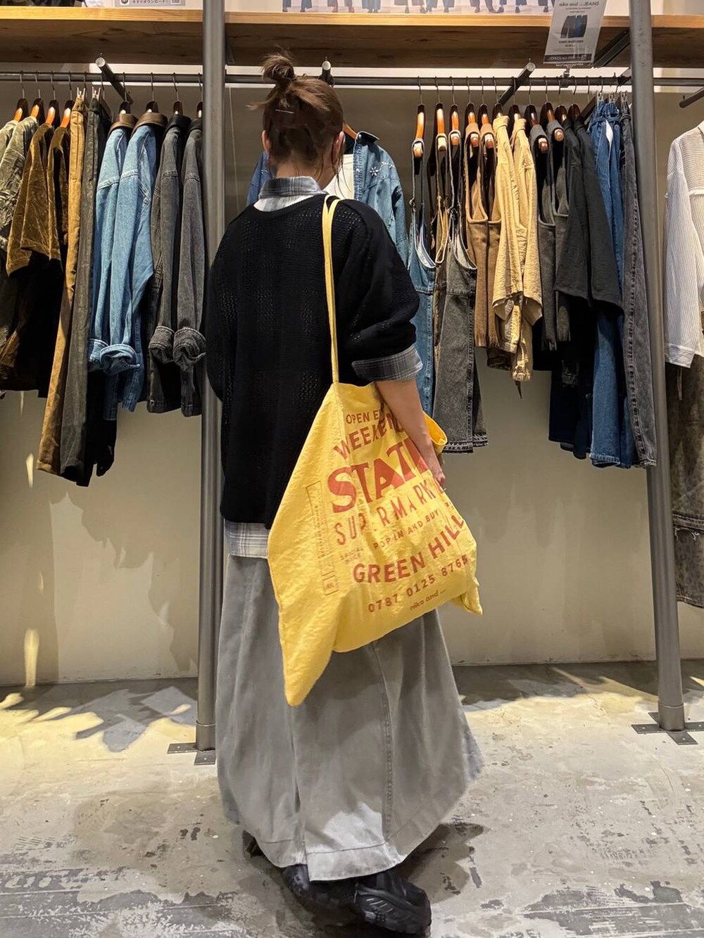 イエロー系のトートバッグ、グレー系のスカート、ブラック系のスニーカーを着用したレディースの秋コーディネートの4枚目の写真