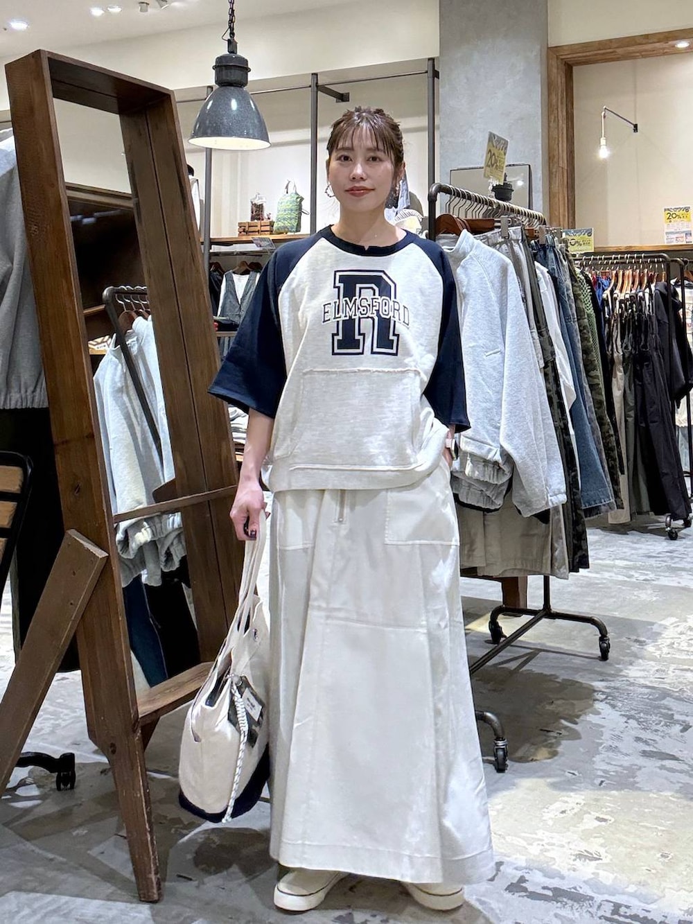 ベージュ系のトートバッグ、ベージュ系のTシャツ/カットソー、ベージュ系のスカートを着用したレディースの春コーディネートの7枚目の写真