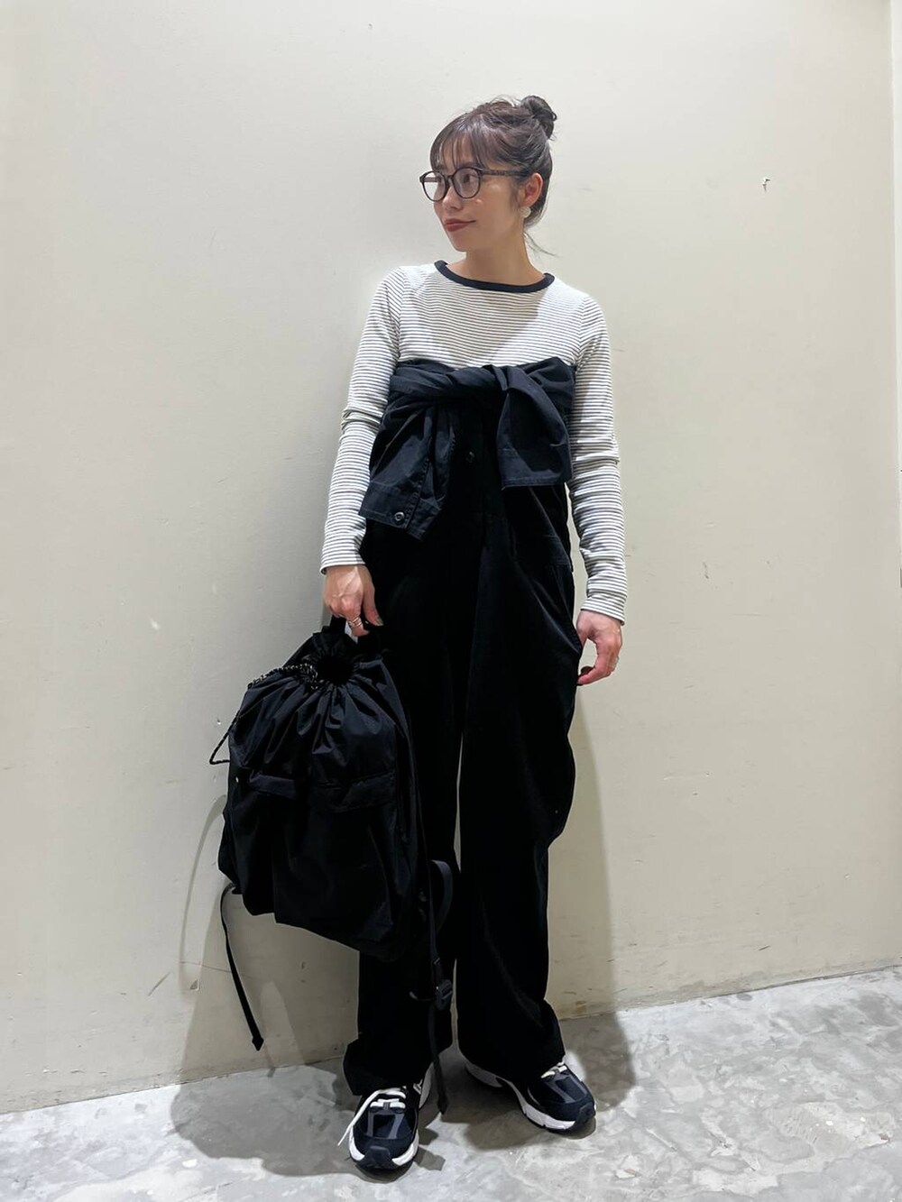 ブラック系のバックパック/リュック、ベージュ系のTシャツ/カットソー、ブラック系のつなぎ/オールインワンを着用したレディースの春コーディネートの2枚目の写真