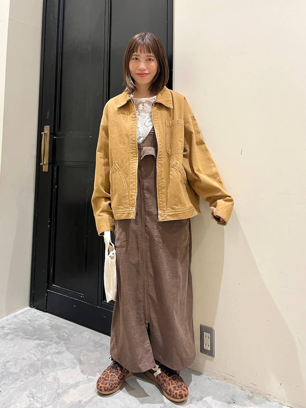 ブラウン系のジャンパースカート、ホワイト系のトートバッグ、ブラウン系のデニムジャケットを着用したレディースの春コーディネートの8枚目の写真