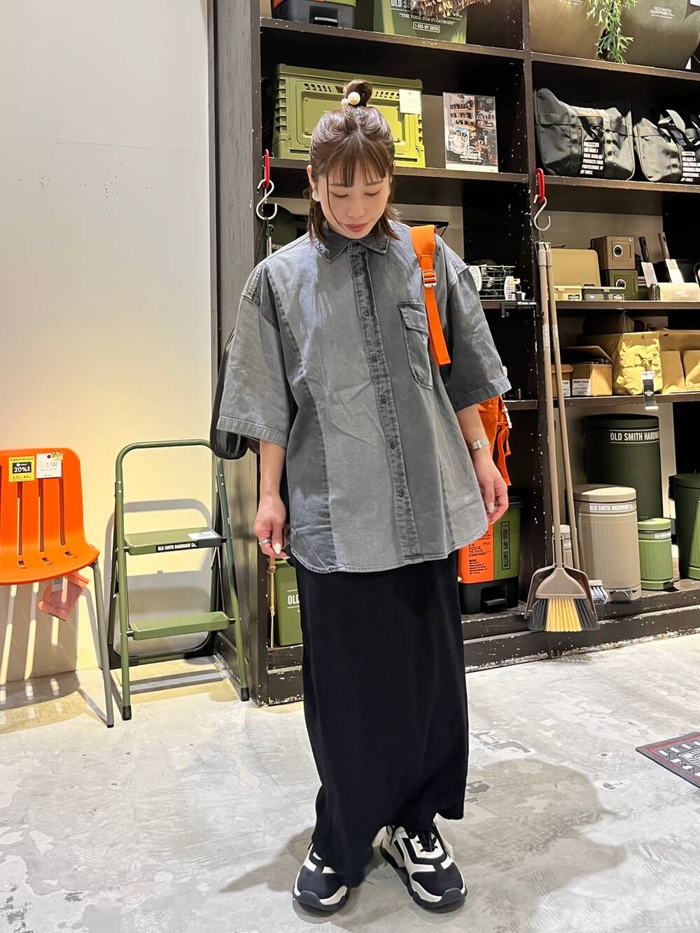 ブラック系のスカート、ブラック系のスニーカー、オレンジ系のバックパック/リュックを着用したレディースの春コーディネートの3枚目の写真