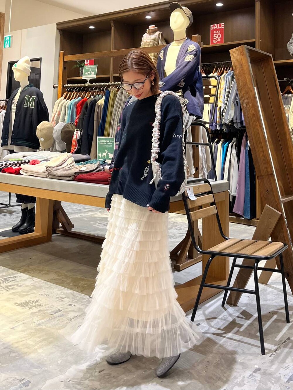 グレー系のブーツ、ホワイト系のスカート、シルバー系のショルダーバッグを着用したレディースの冬コーディネートの3枚目の写真