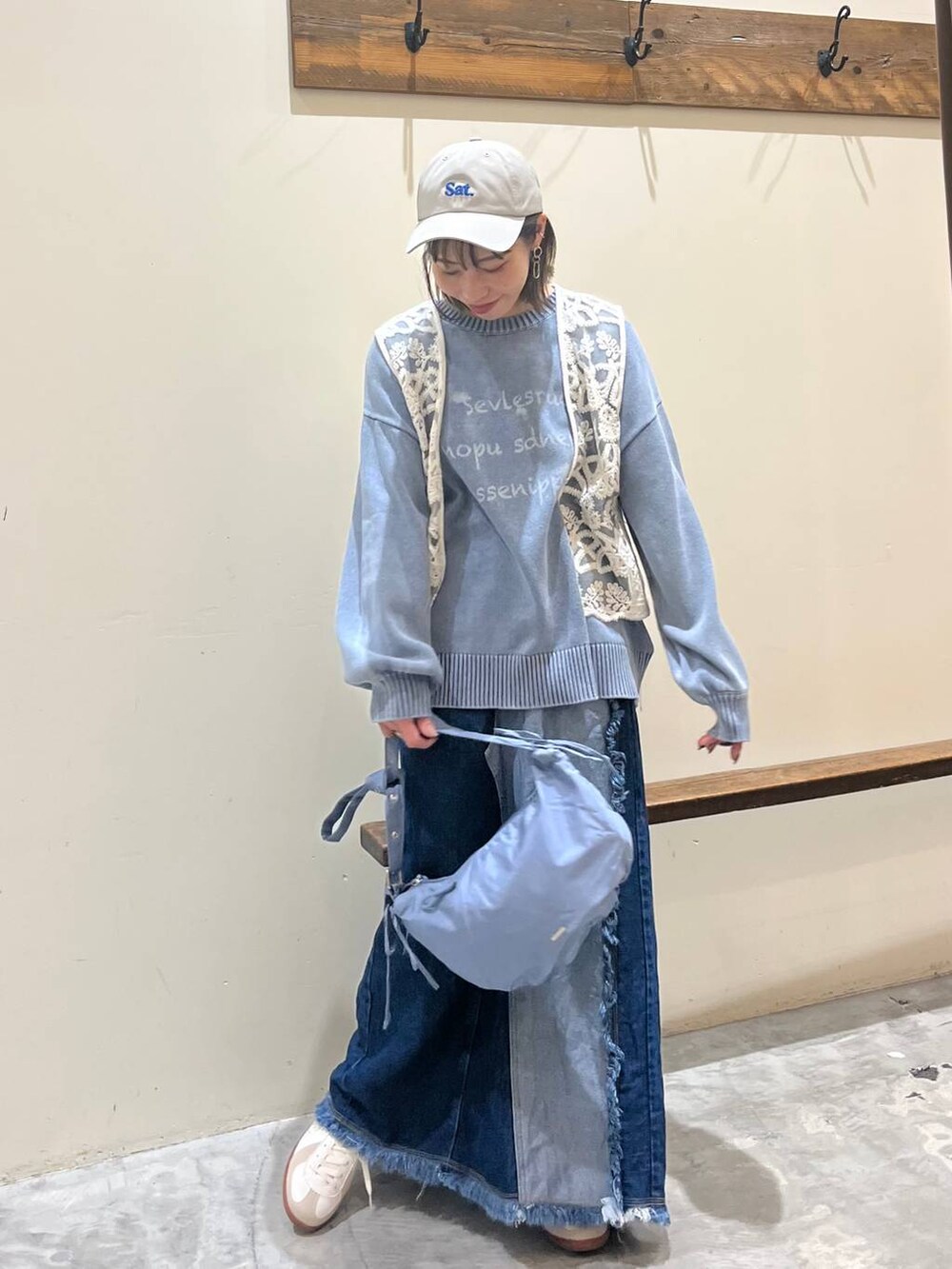 ベージュ系のスニーカー、ブルー系のデニムスカート、ブルー系のショルダーバッグを着用したレディースの冬コーディネートの4枚目の写真