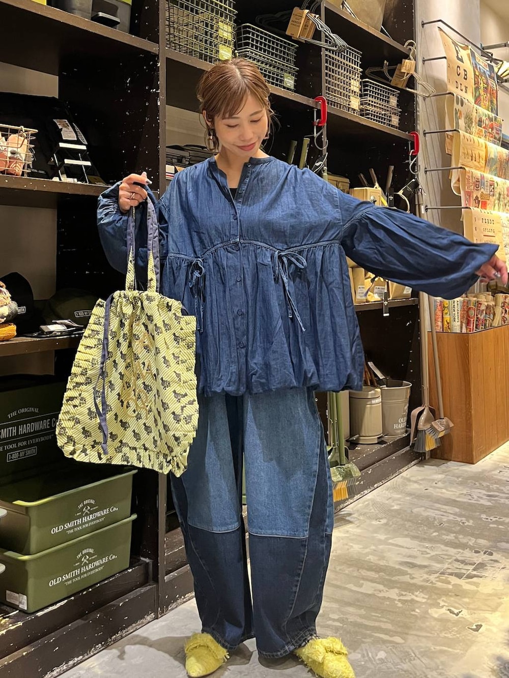 ベージュ系のトートバッグ、ブルー系のデニムパンツ、イエロー系のバレエシューズを着用したレディースの秋コーディネートの5枚目の写真