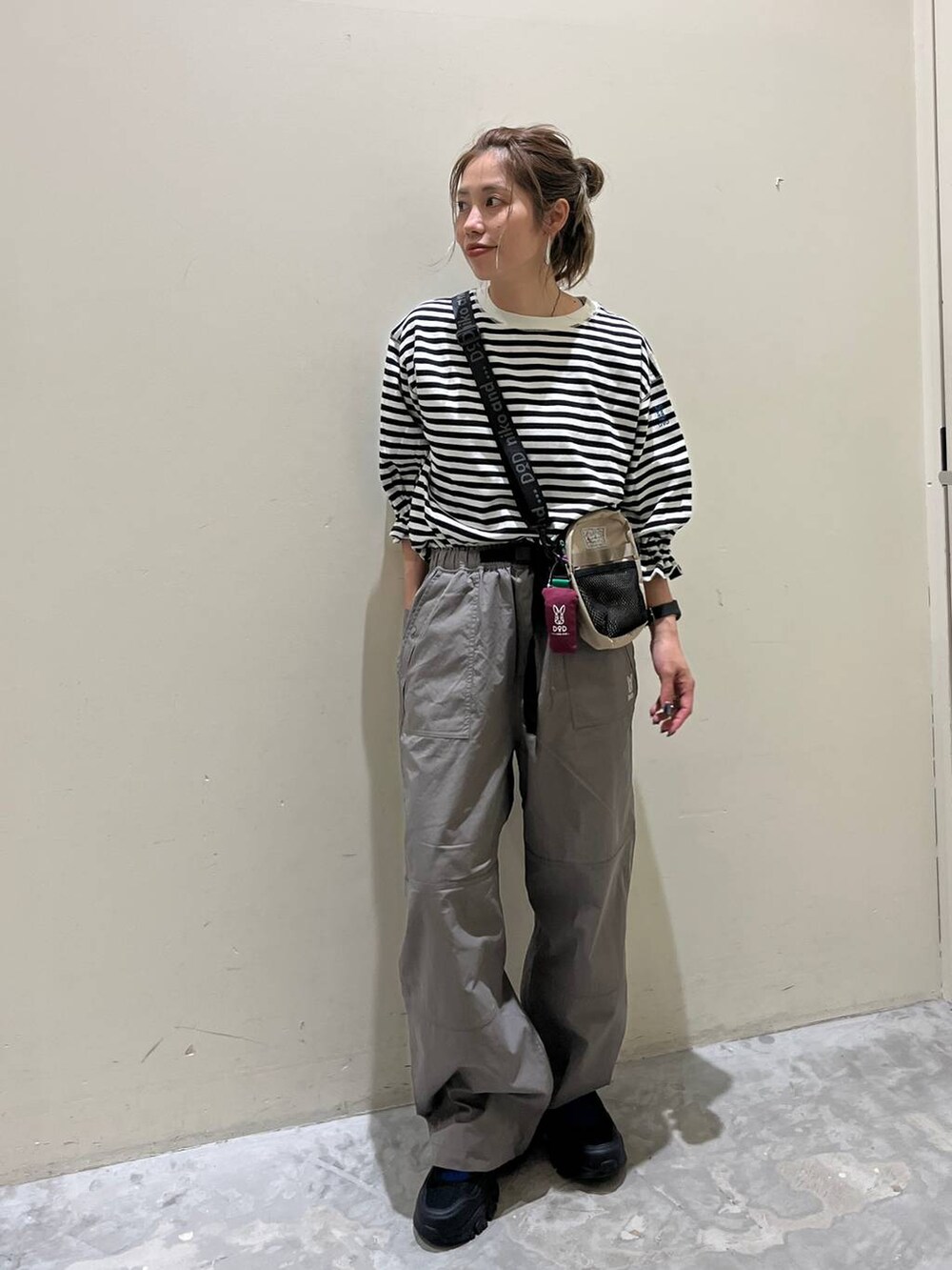 グレー系のその他パンツ、ブラック系のスニーカー、ホワイト系のTシャツ/カットソーを着用したレディースの春コーディネートの6枚目の写真