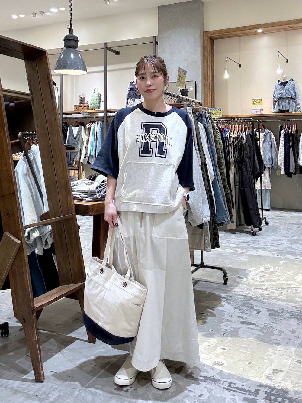 ベージュ系のトートバッグ、ベージュ系のTシャツ/カットソー、ベージュ系のスカートを着用したレディースの春コーディネートの3枚目の写真