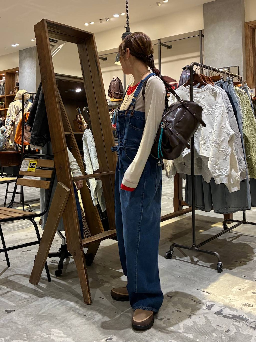 ブラウン系のボストンバッグ、ベージュ系のTシャツ/カットソー、ブルー系のサロペット/オーバーオールを着用したレディースの冬コーディネートの5枚目の写真