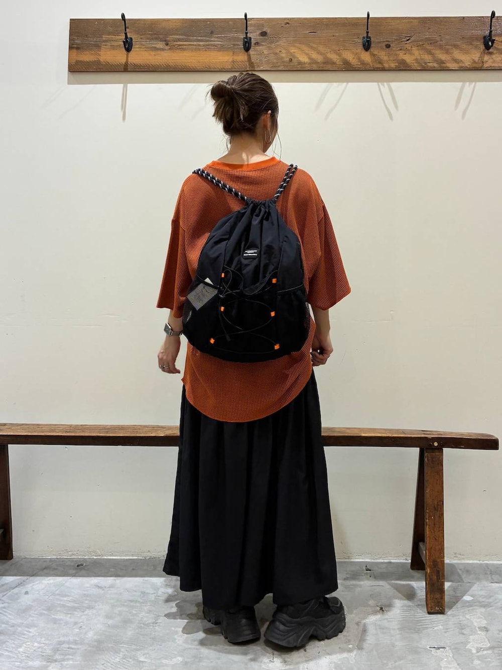 ブラック系のスカート、オレンジ系のTシャツ/カットソー、ブラック系のバックパック/リュックを着用したレディースの夏コーディネートの3枚目の写真