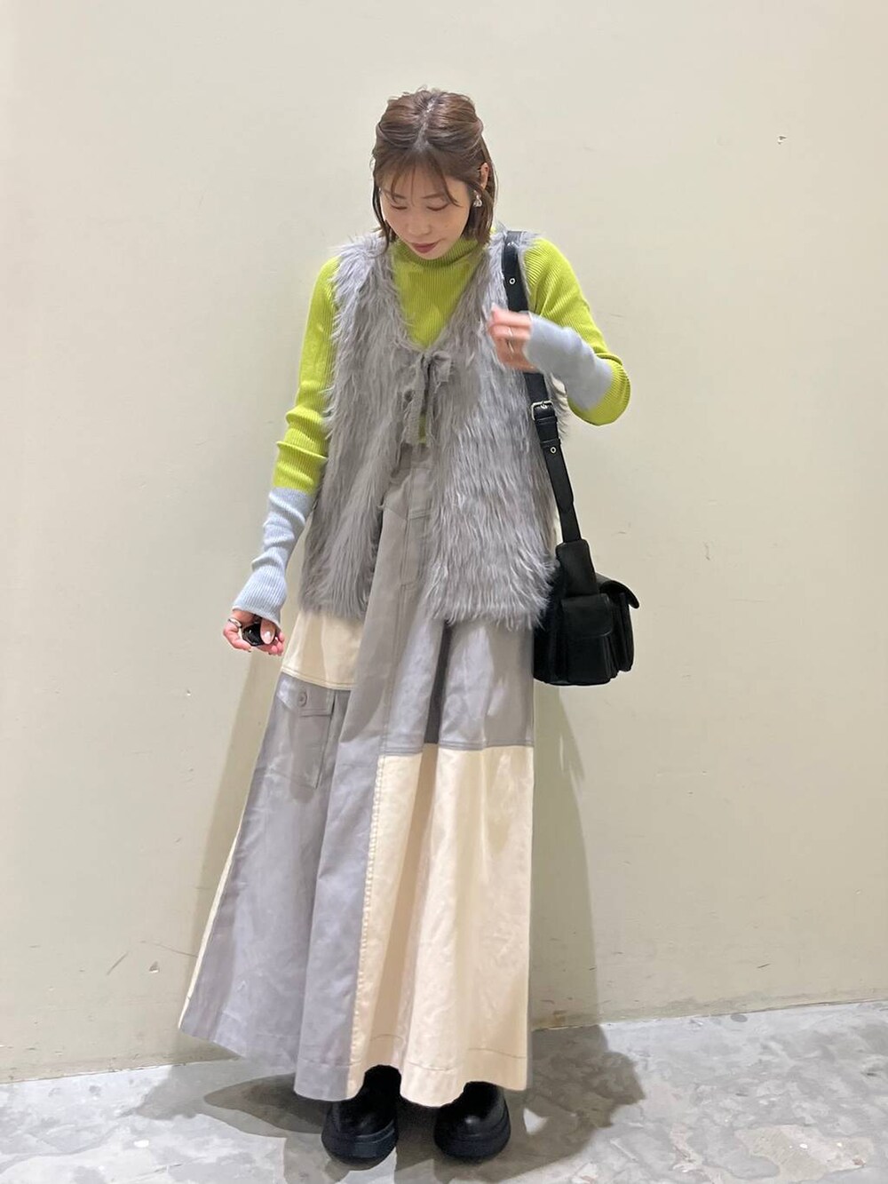 グリーン系のニット/セーター、ブラック系のブーツ、ブラック系のショルダーバッグを着用したレディースの冬コーディネートの4枚目の写真