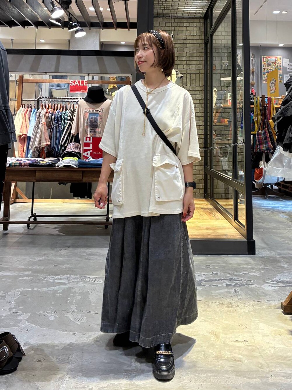 グレー系のスカート、ベージュ系のTシャツ/カットソー、ブラック系のショルダーバッグを着用したレディースの夏コーディネートの4枚目の写真