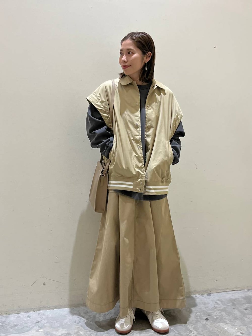 ベージュ系のスニーカー、ベージュ系のスタジャン、ベージュ系のスカートを着用したレディースの冬コーディネートの8枚目の写真