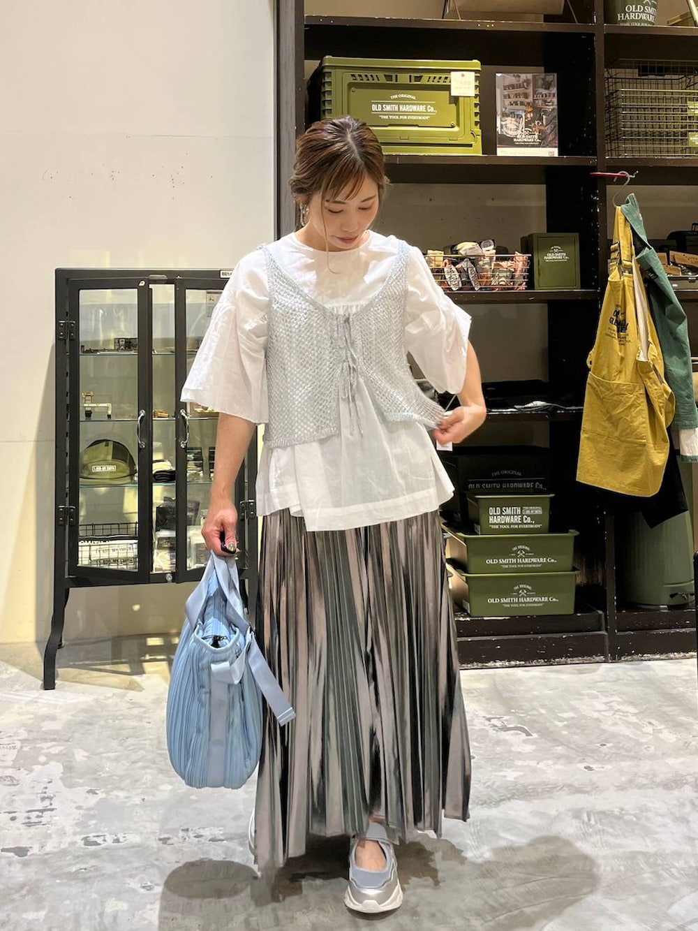 グレー系のスカート、ブルー系のトートバッグ、シルバー系のスニーカーを着用したレディースの夏コーディネートの4枚目の写真