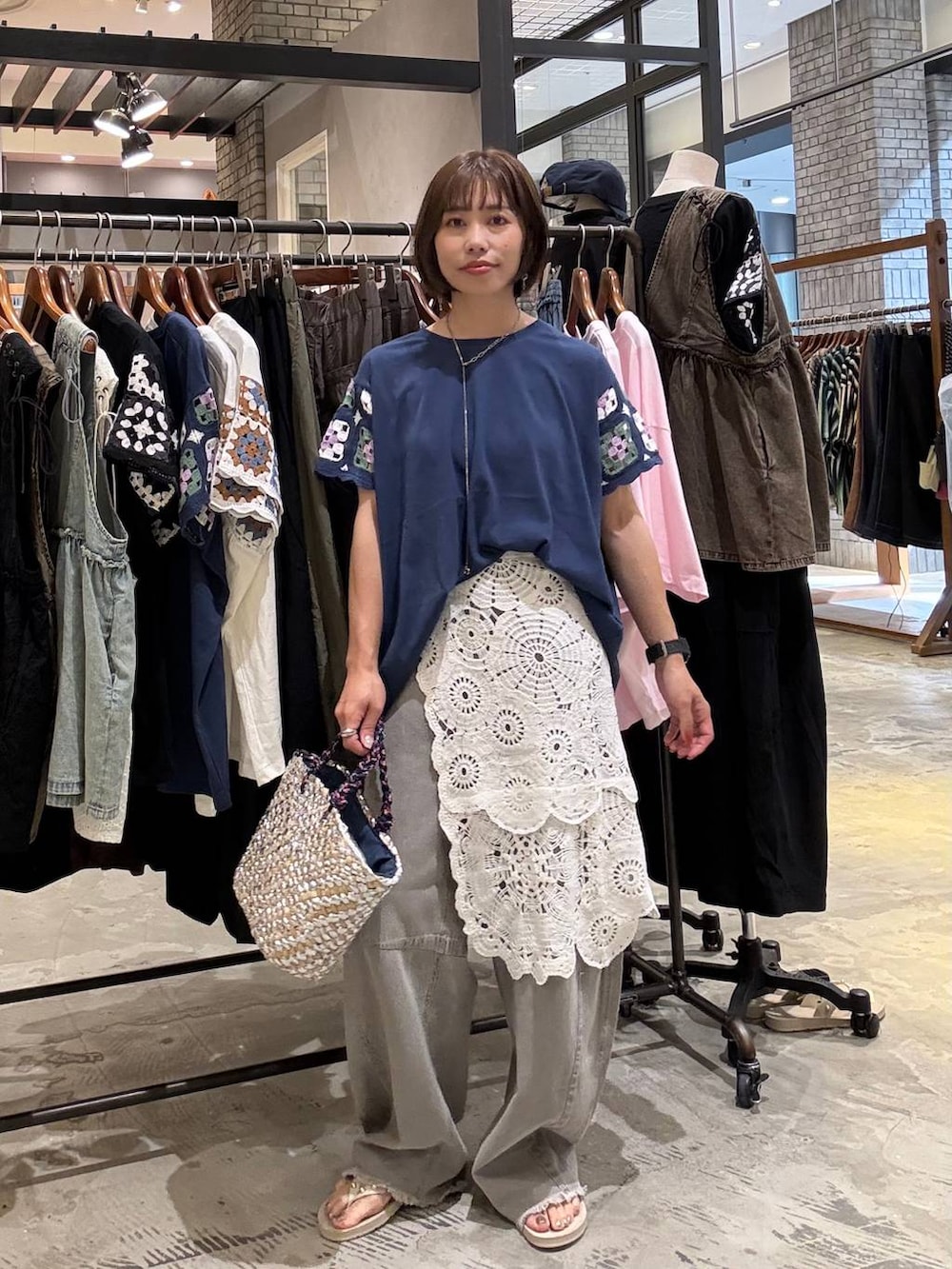 グレー系のその他パンツ、ベージュ系のサンダル、グレー系のかごバッグを着用したレディースの夏コーディネートの3枚目の写真